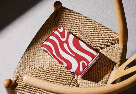 Mockup of customizable closed small rectangular cardboard box on chair