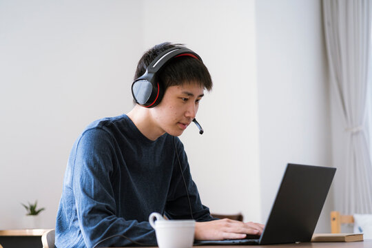 インカムを着けてパソコンを見る若い日本人男性