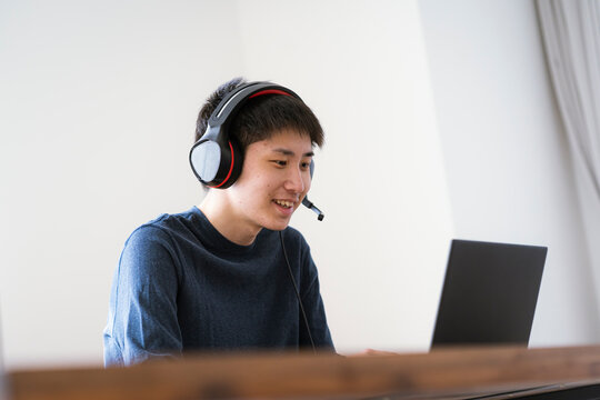 インカムを着けてパソコンを見る若い日本人男性