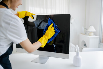 Young woman using a computer cleaning cloth to disinfect the office.office cleaning staff cleaning maid