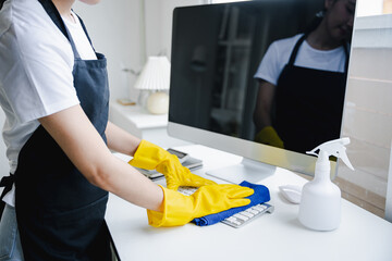 Young woman using a computer keyboard cleaning cloth to disinfect the office.office cleaning staff cleaning maid