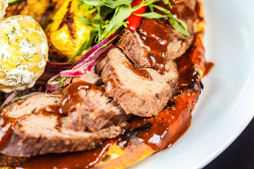 A plate of meat and vegetables with sauce on it