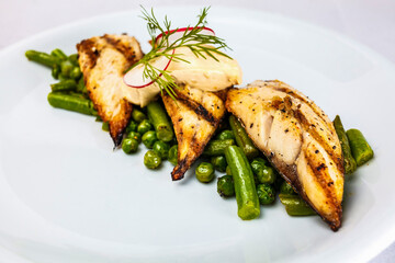 A plate of fresh, roasted fish steak surrounded by green beans, peas and other vegetables - a healthy meal for wellbeing.