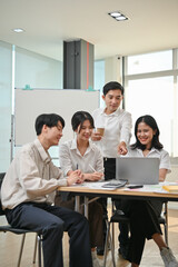 A smart Asian businessman is training and coaching young employees in the office.