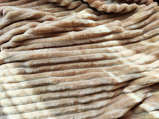 Closeup soft, fluffy sleeping beige blanket or plaid. Crumpled fabric. Abstract background and texture with frame. Partial focus