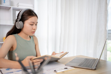 Obraz premium Young female student reading a book in a private office, Self study, Textbooks from books, Find out more, In the office there is a computer or laptop placed on the table, Study.