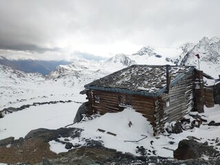 Abandoned Cabin on top of the mountain in alps with snow and sky with clouds