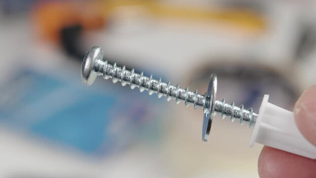 White plastic dowels with metal nail in hand in workshop