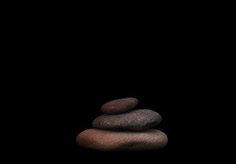 Fototapeta na wymiar Pyramid of stacked stones, black background