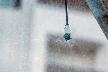 Closeup of agricultural sprinkler head spraying water drops at field