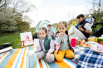 Happy young family, four kids having fun and enjoying outdoor on picnic blanket at garden spring park, relaxation.