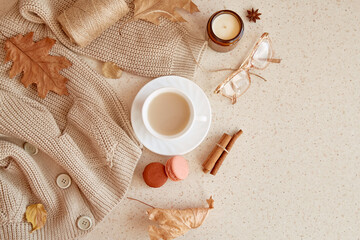 Autumn woman cozy lifestyle - sweater, glasess, candle. Atmospheric coffee time among fall leaves, cinnamon sticks, macaroons . Copy space.