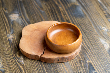 Fototapeta na wymiar Wooden bowl on wooden table, empty round bowl for groceries and food