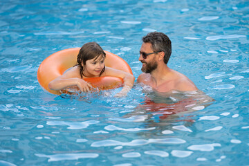 Cute excited child with dad in summer swimming pool. Father and child having fun in summer pool. Father and son swimming in pool. Family at aquapark. Dad and son in pool on summer weekend.