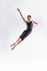 Fototapeta na wymiar Professional Ballet Dancer Young Caucasian Athletic Man in Black Suit Posing Flying Dancing in Studio On White.