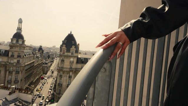Close up of a young woman's hand going up outdoor stairs, with the Paris cityscape in the background, France