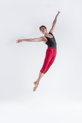 Fototapeta na wymiar Modern Ballet Dancer. Contemporary Art Ballet With Young Flexible Athletic Man Posing in Flying Dance Pose in Studio