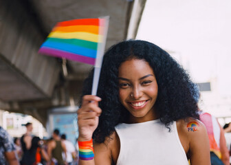 A young black woman with rainbow tattoo stickers and showing symbols of homosexuality in pride parade.