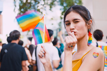 A young woman with rainbow tattoo stickers and showing symbols of homosexuality in pride parade.
