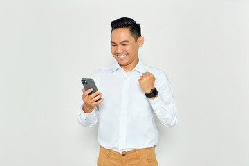 Happy young Asian man in formal wear using mobile phone for trading or chatting and making winning gesture isolated on white background