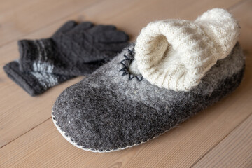 Woolen house shoes, socks and gloves lie on the home wooden floor