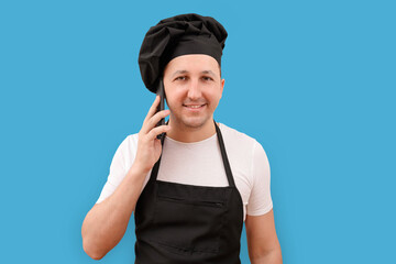 Male chef talking on the phone on a blue background. Cooking and people concept