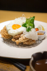 Close up of Japanese fried chicken with fried egg on wood table