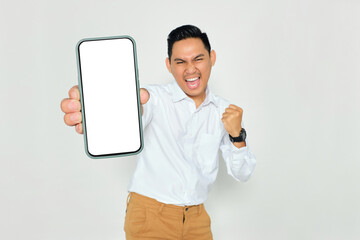 Mockup. Excited young Asian man in formal wear showing mobile phone with blank white screen and...