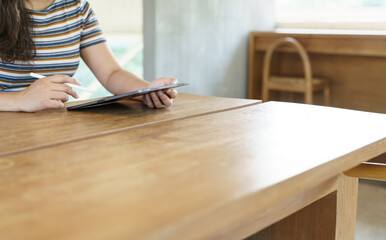 Woman holding a book device reading on e-book on digital tablet device or social media apps online ecommerce.