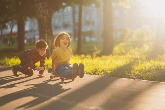Cheerful siblings skateboarding on street