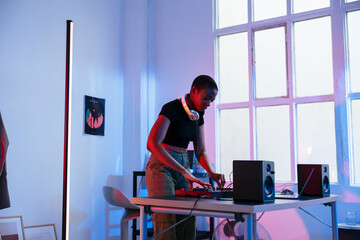 Young Dj mixing music through sound mixer at home