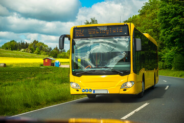 Yellow bus moving on road near grass
