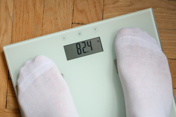 Odchudzanie, mężczyzna stojący na elektronicznej wadze do pomiaru masy ciała  - obrazy, fototapety, plakaty
