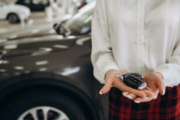woman holding a car key in the hands of a car dealership