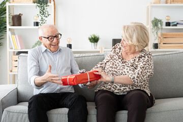 Senior woman giving present to happy husband