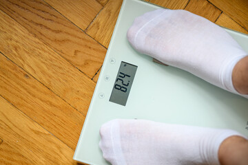 Stopy na wadze elektronicznej, pokazującej wynik 82 kg