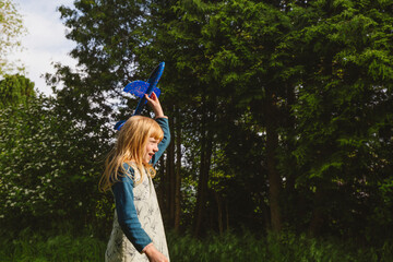 Happy blond girl playing with airplane toy