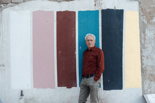 Senior businessman leaning on multi colored wall