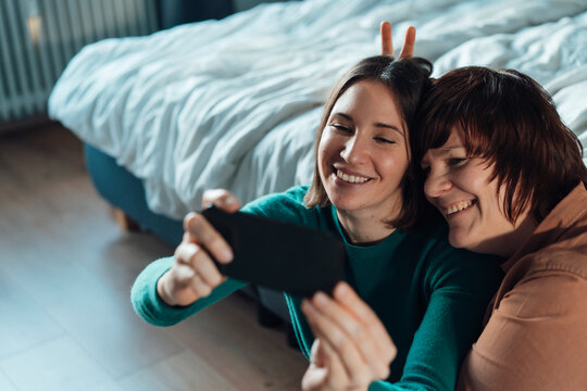 Happy lesbian couple taking selfie through smart phone at home