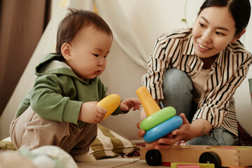 Mother giving toy to daughter crouching at home