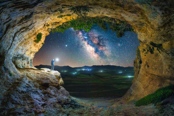 Milky way over the Bronze Age Zaen Cave in Campo de San Juan. A man with a lantern is watching the Milky Way over the famous Zaen Cave (Bronze Age). Moratalla, Murcia, Spain