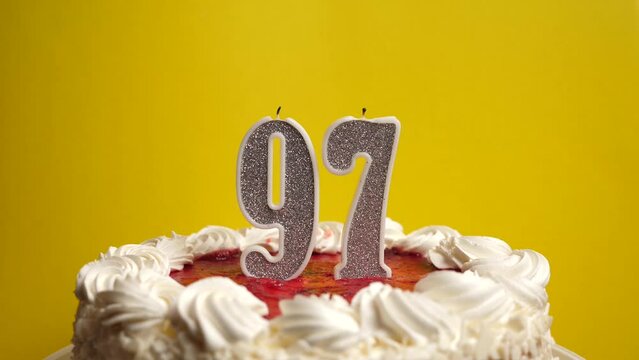 A candle in the form of the number 97, stuck in a holiday cake, is blown out. Celebrating a birthday or a landmark event. The climax of the celebration.
