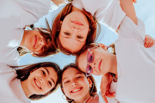 Happy teenage friends huddling below sky