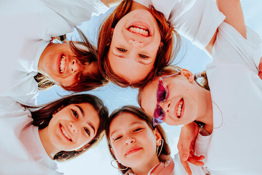 Smiling teenage friends huddling below sky