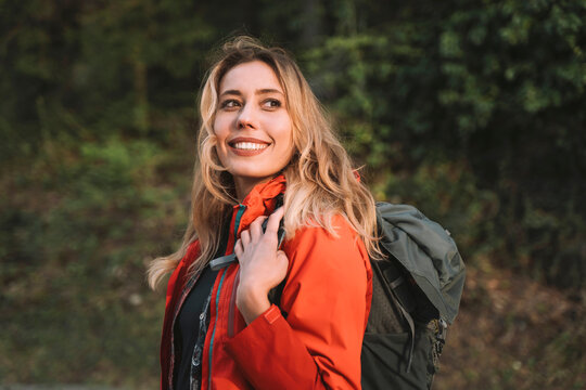 Blond happy woman with backpack in forest