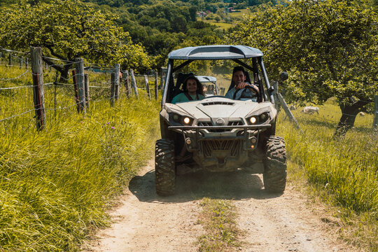 Happy friends driving buggy on dirt road in forest