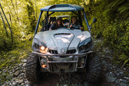 Young smiling friends riding buggy at forest