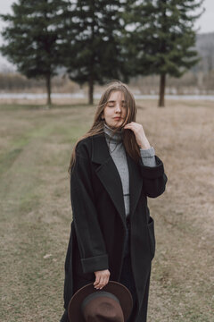 Young woman wearing long coat standing on field