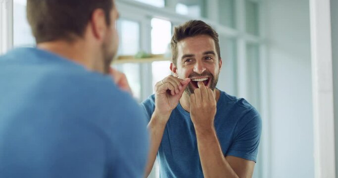 Reflection, man in bathroom with dental floss and morning routine of cleaning teeth and self care. Grooming, cleansing mouth and flossing, male in mirror with smile and getting ready with fresh face.