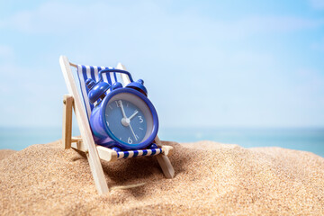 Time to relax, alarm clock relaxing on deck chair on beach